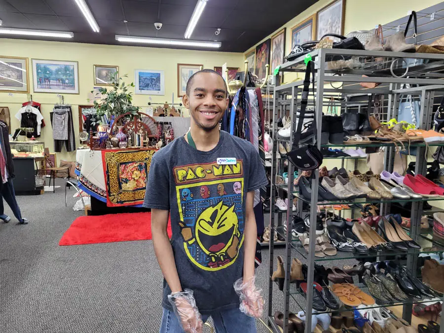 Man wearing a pac-man shirt smiling for camera in thrift store