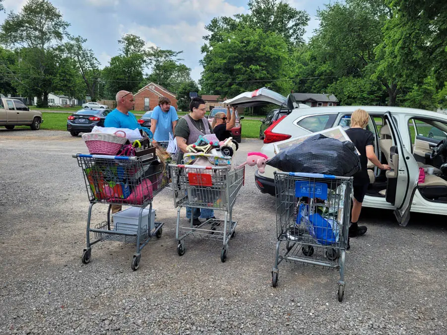 Three carts full of random items outside in parking lot in front of car
