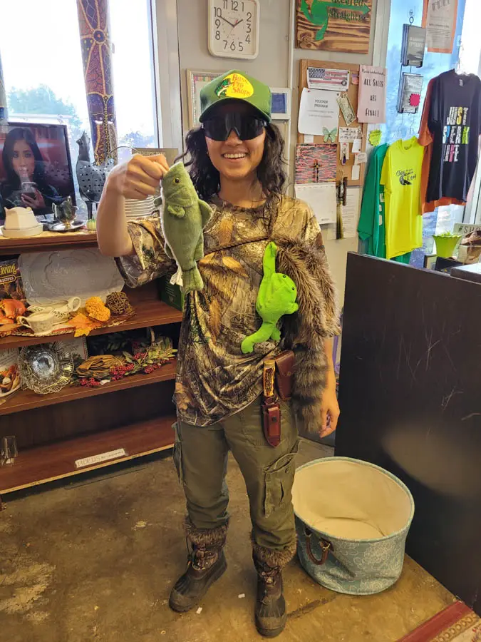 Young lady holding up stuffed animal fish in hunting attire