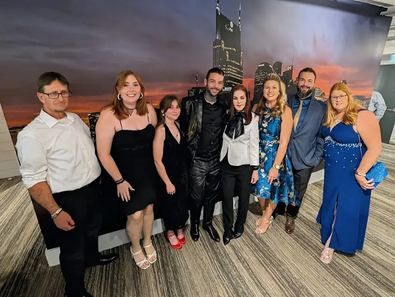 People in formal wear standing in front of city backdrop posing for a picture