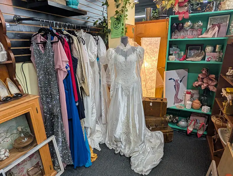 Wedding dress on mannequin, next to rack of dresses