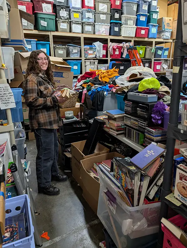 Person standing surrounded by thrift store items