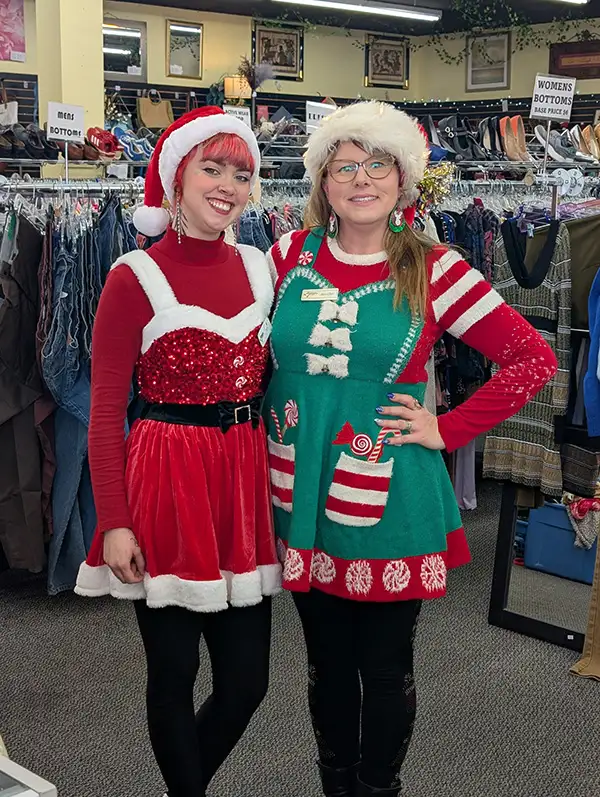 Two people in decorative holiday clothes posing for picture