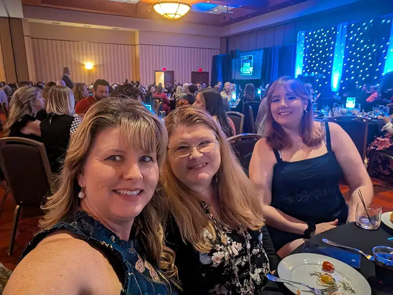 Three people at gala table posing for picture