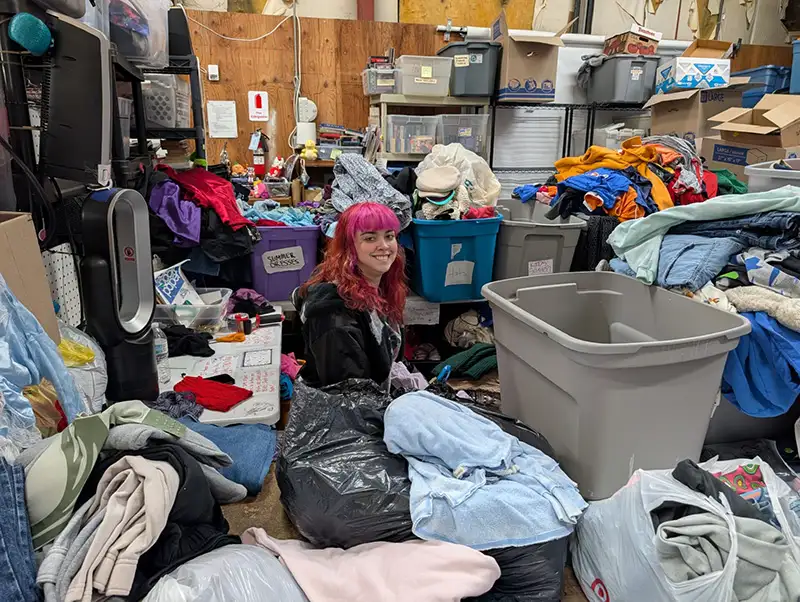 Person with pink hair surrounded by clothing