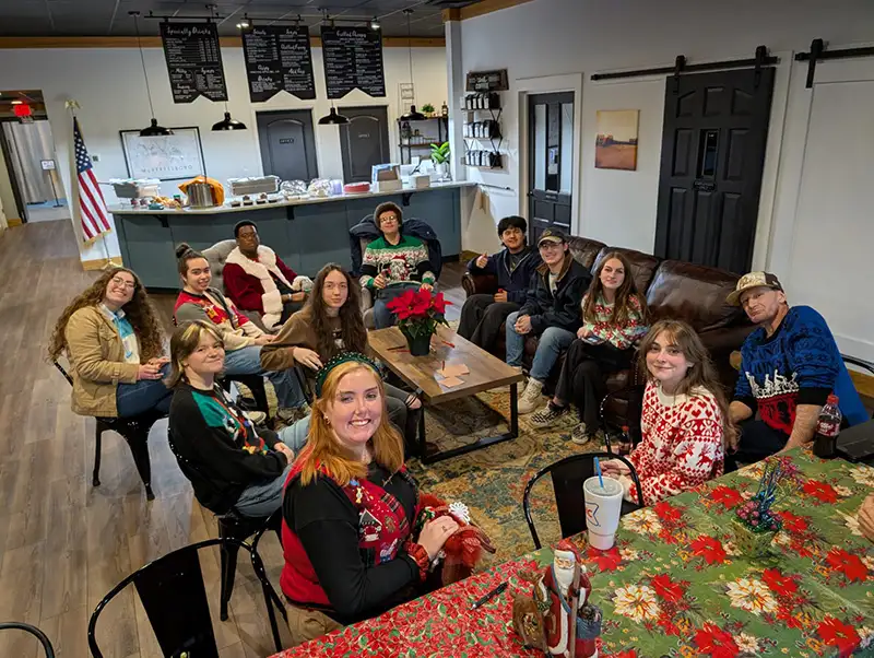 Group of employees in holiday clothing sitting around a table
